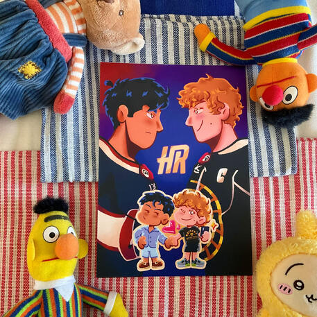 Foto de la print de Heated Rivalry. A modo de decoración a su alrededor hay: peluches de Epi y Blas de Barrio Sésamo, un peluche de un osito marrón y un peluche de Usagi de la serie Chiikawa.