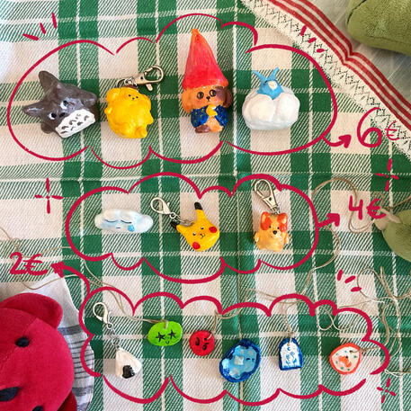 Foto de varias figuras de arcilla de secado al aire. A modo de decoración a su alrededor hay puesto un mantelito de cuadros verde y un peluche de un osito rojo.