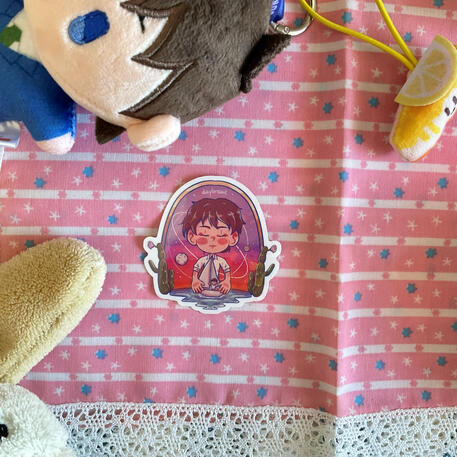 Foto de la pegatina de Ikoku Nikki. A modo de decoración a su alrededor hay: un peluche de un perro blanco y un peluche de Shinichi del manga Detective Conan.